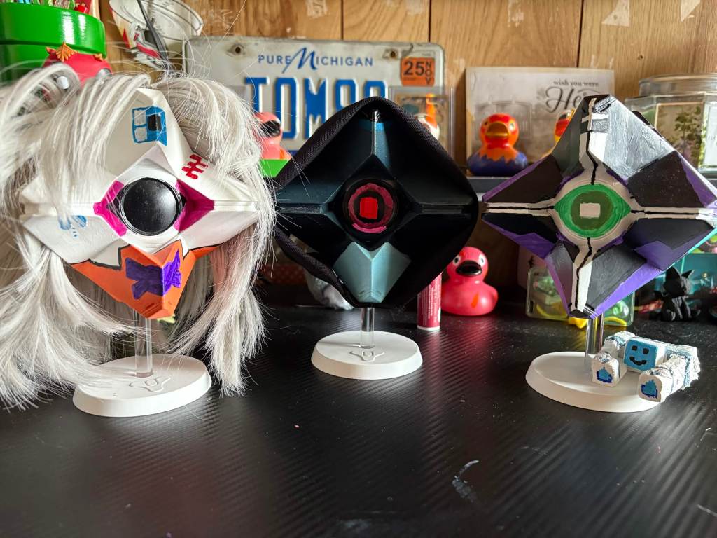 An image of three Destiny 2 x Marathon the Game crossover pieces, hand painted, sewn, glued, and modeled (with clay) by my of Glitch/Vandal, Void/Assasin, and Triage plus Squish.